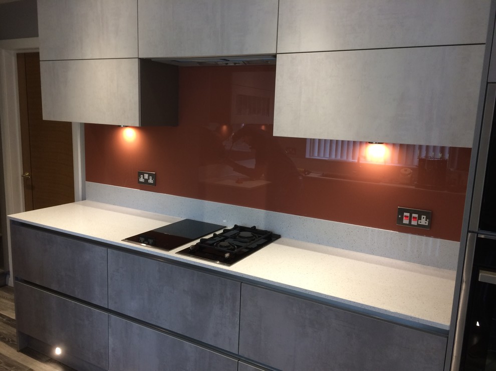 Mittelgroße Moderne Küche mit Küchenrückwand in Metallic und Glasrückwand in Cheshire