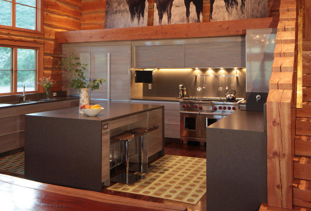 Foto på ett funkis u-kök, med släta luckor, grå skåp, stänkskydd med metallisk yta, stänkskydd i metallkakel, rostfria vitvaror, mellanmörkt trägolv och en köksö