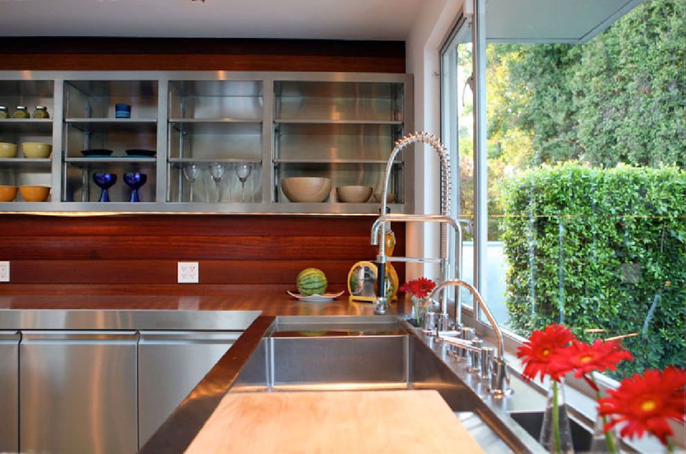 Exempel på ett modernt kök, med en integrerad diskho, öppna hyllor, skåp i rostfritt stål och bänkskiva i rostfritt stål