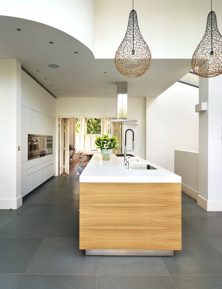 This is an example of a contemporary kitchen in Oxfordshire with a submerged sink, flat-panel cabinets, white cabinets, stainless steel appliances and an island.