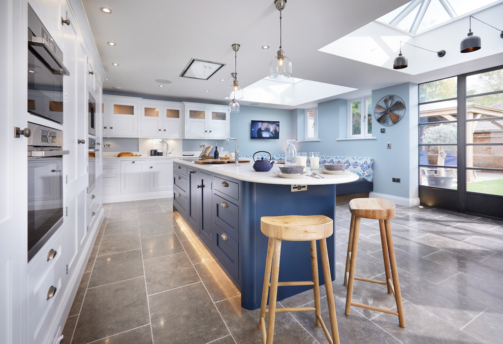 Photo of a large classic l-shaped kitchen/diner in Other with shaker cabinets, quartz worktops, white splashback, stainless steel appliances, brown floors, white worktops, limestone flooring, a built-in sink, white cabinets and an island.