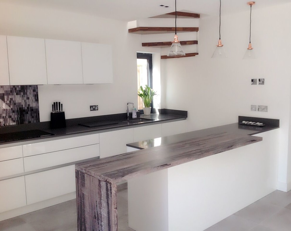 Photo of a contemporary u-shaped kitchen in Surrey with an integrated sink, flat-panel cabinets, white cabinets, quartz worktops, multi-coloured splashback, glass sheet splashback, integrated appliances, porcelain flooring and an island.