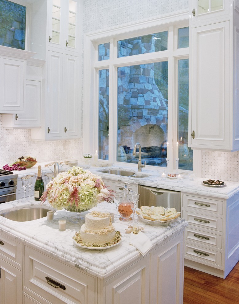 Cottage chic l-shaped kitchen photo in Other with stainless steel appliances, an undermount sink, raised-panel cabinets, white cabinets, white backsplash, marble countertops and marble backsplash