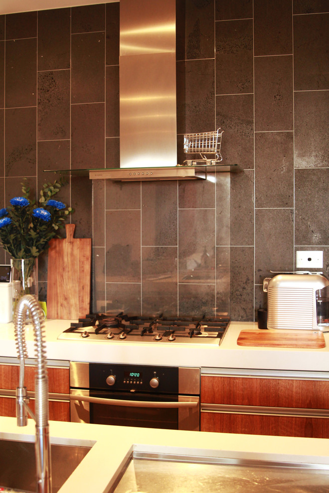 Foto på ett eklektiskt kök, med en undermonterad diskho, skåp i mörkt trä, bänkskiva i kvarts, grått stänkskydd, stänkskydd i sten, rostfria vitvaror, betonggolv och en köksö