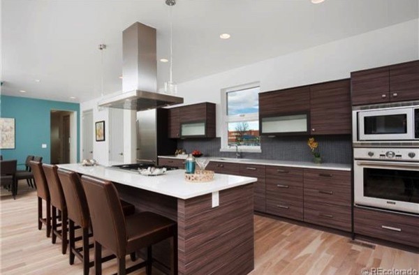 This is an example of a large contemporary single-wall kitchen/diner in San Diego with a submerged sink, flat-panel cabinets, dark wood cabinets, engineered stone countertops, grey splashback, light hardwood flooring and an island.