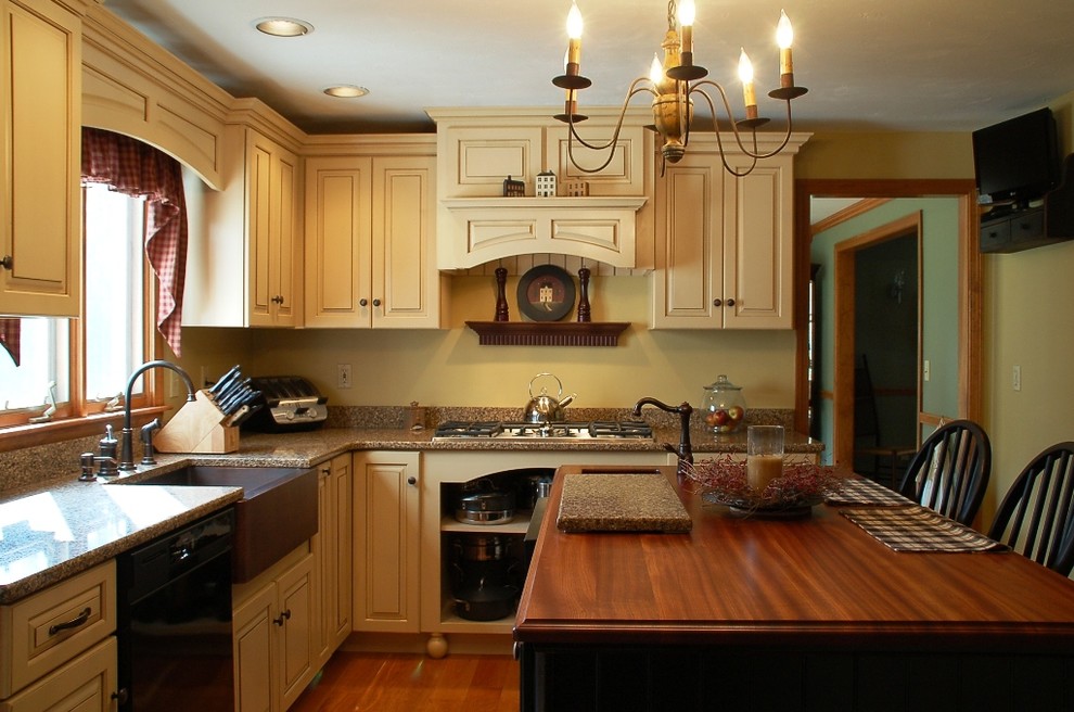 Landhausstil Küche in L-Form mit Landhausspüle, profilierten Schrankfronten, gelben Schränken, Quarzwerkstein-Arbeitsplatte, Küchenrückwand in Gelb, schwarzen Elektrogeräten, braunem Holzboden und Kücheninsel in Boston