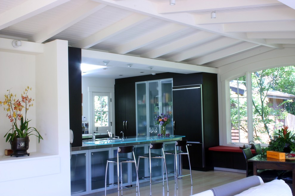 Стильный дизайн: кухня-гостиная в современном стиле с стеклянными фасадами, стеклянной столешницей, техникой под мебельный фасад, черно-белыми фасадами и барной стойкой - последний тренд