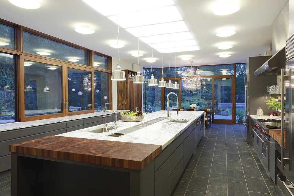 Cette image montre une très grande cuisine design avec un placard à porte plane, des portes de placard grises et îlot.