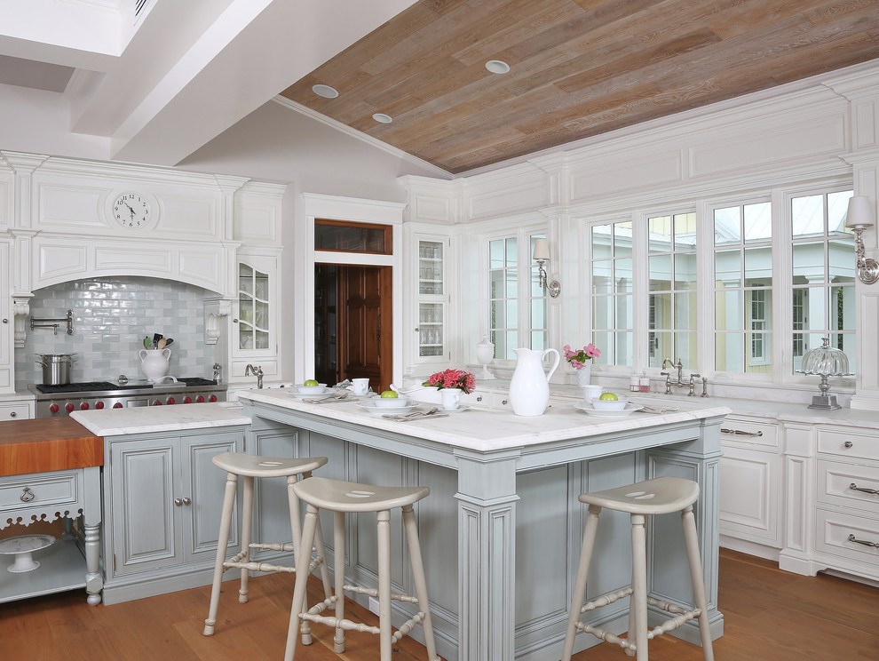 Exempel på ett stort klassiskt kök, med luckor med profilerade fronter, vita skåp, en rustik diskho, marmorbänkskiva, stänkskydd i glaskakel, integrerade vitvaror, mellanmörkt trägolv och en köksö