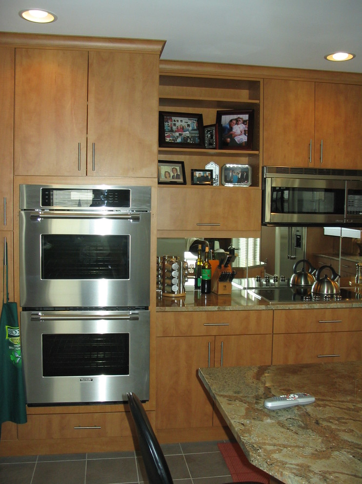 This is an example of a medium sized contemporary l-shaped kitchen/diner in Baltimore with a built-in sink, flat-panel cabinets, light wood cabinets, marble worktops, stainless steel appliances, ceramic flooring and an island.