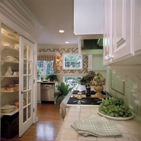 Foto på ett stort vintage kök, med en dubbel diskho, luckor med upphöjd panel, vita skåp, kaklad bänkskiva, beige stänkskydd, stänkskydd i stenkakel, rostfria vitvaror, ljust trägolv och en köksö