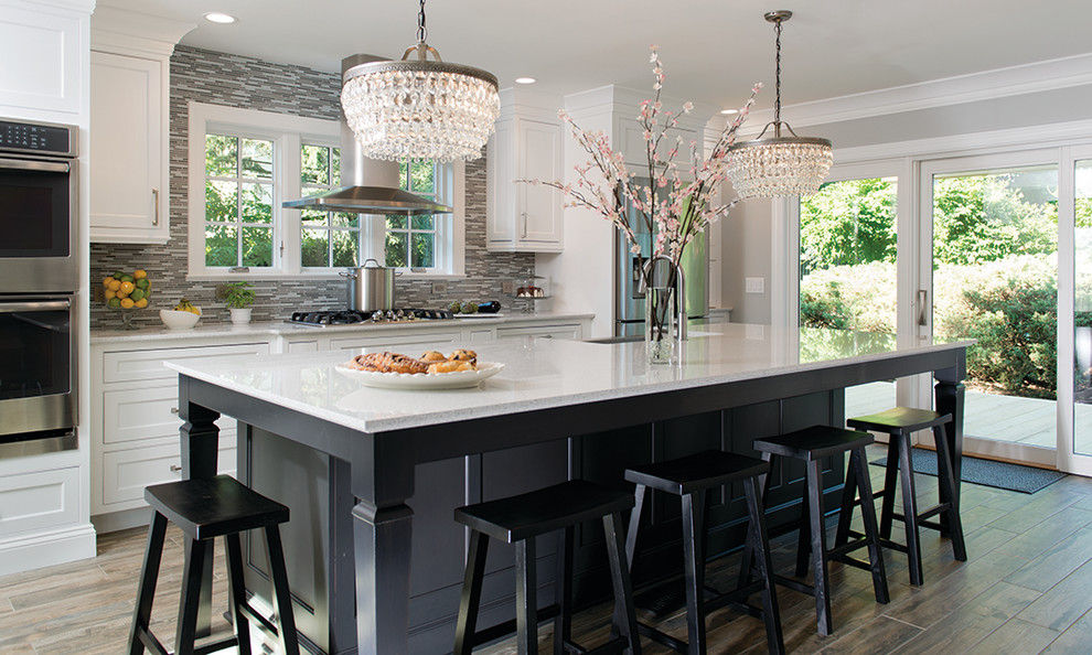 Large elegant galley porcelain tile eat-in kitchen photo in New York with a farmhouse sink, beaded inset cabinets, white cabinets, quartz countertops, gray backsplash, glass tile backsplash, stainless steel appliances and an island