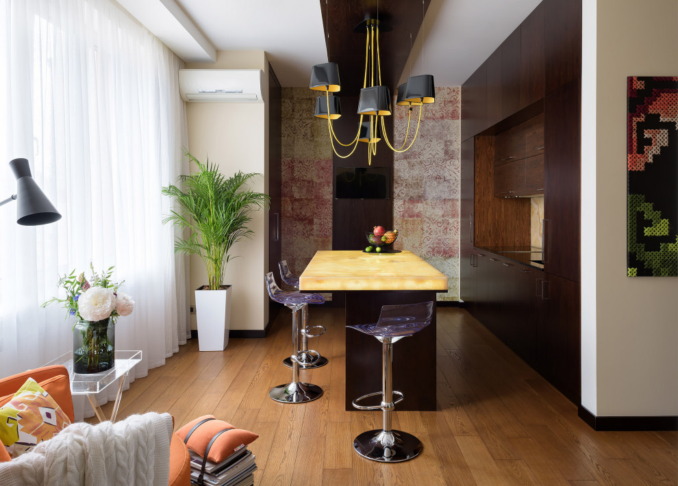Mittelgroße Moderne Wohnküche mit flächenbündigen Schrankfronten, dunklen Holzschränken, Onyx-Arbeitsplatte, Küchenrückwand in Gelb, braunem Holzboden, Kücheninsel, beigem Boden und gelber Arbeitsplatte in Sonstige