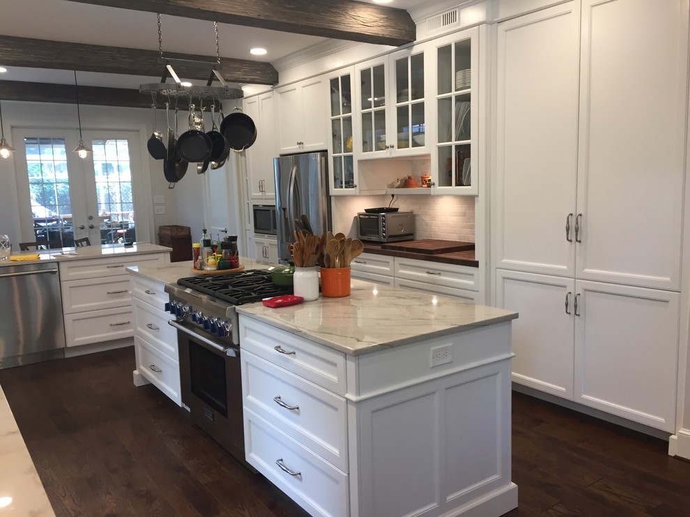 Photo of a large traditional u-shaped kitchen/diner in Jacksonville with a belfast sink, recessed-panel cabinets, white cabinets, marble worktops, white splashback, metro tiled splashback, stainless steel appliances, dark hardwood flooring and an island.