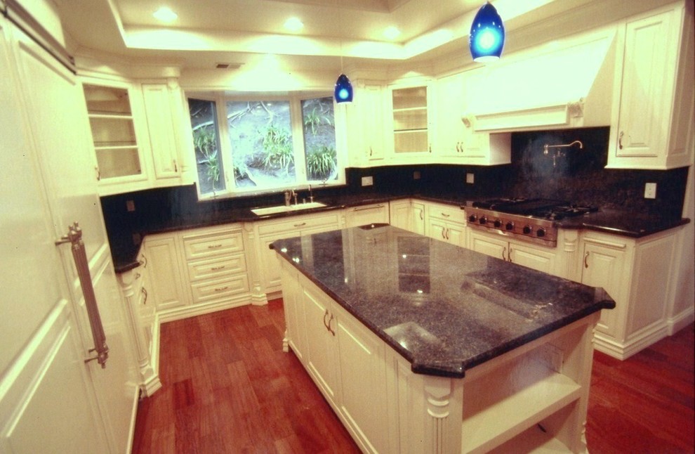Photo of a traditional u-shaped enclosed kitchen in Los Angeles with a submerged sink, raised-panel cabinets, white cabinets, granite worktops, blue splashback, white appliances, medium hardwood flooring and multiple islands.