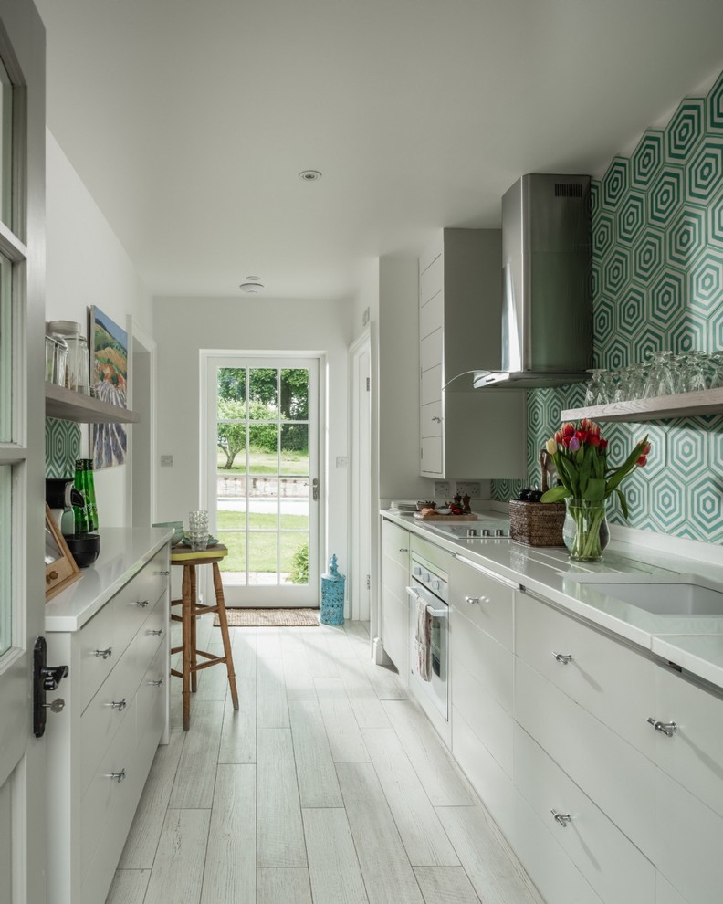 Photo of a medium sized bohemian galley kitchen in Hampshire with a submerged sink, flat-panel cabinets, white cabinets, stainless steel appliances, white worktops, multi-coloured splashback and beige floors.