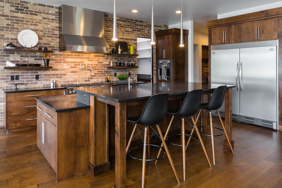 This is an example of a large contemporary l-shaped kitchen/diner in Boise with a submerged sink, flat-panel cabinets, medium wood cabinets, granite worktops, brown splashback, stainless steel appliances, medium hardwood flooring and an island.