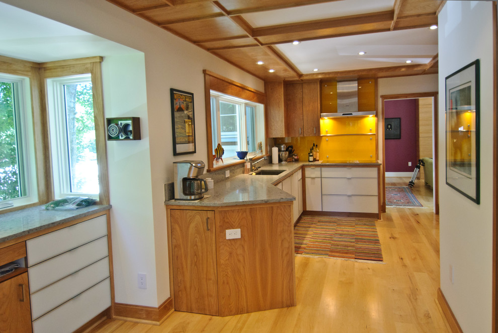 Transitional u-shaped enclosed kitchen photo in DC Metro with an undermount sink, flat-panel cabinets, light wood cabinets, solid surface countertops, orange backsplash, glass sheet backsplash and stainless steel appliances