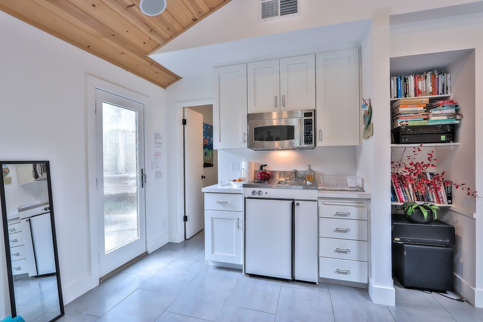 Foto de cocina comedor lineal moderna extra grande con puertas de armario blancas, salpicadero blanco, electrodomésticos blancos, suelo gris y encimeras blancas