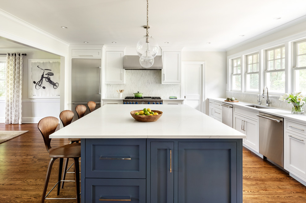 Inspiration for a transitional medium tone wood floor kitchen remodel in New York with an undermount sink, shaker cabinets, white cabinets, white backsplash, stainless steel appliances, an island and white countertops