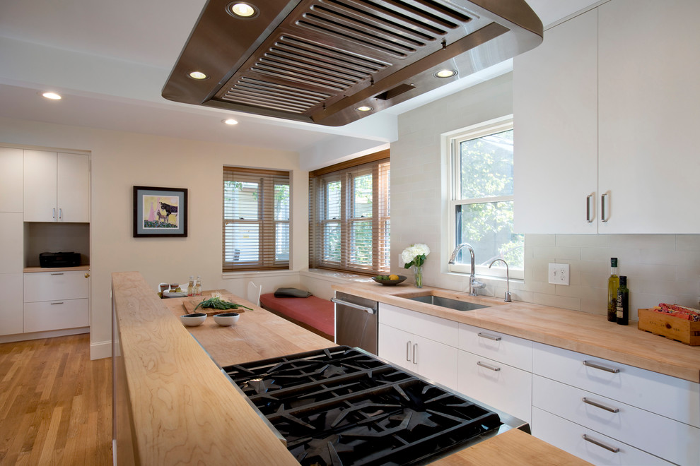Exempel på ett litet klassiskt kök, med en undermonterad diskho, släta luckor, vita skåp, träbänkskiva, beige stänkskydd, stänkskydd i keramik, rostfria vitvaror, mellanmörkt trägolv och en köksö