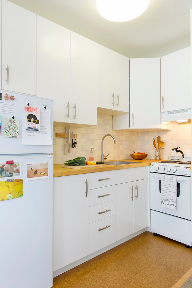 Idée de décoration pour une cuisine design avec un placard à porte plane, une crédence en carrelage métro, un plan de travail en bois, un électroménager blanc et des portes de placard blanches.