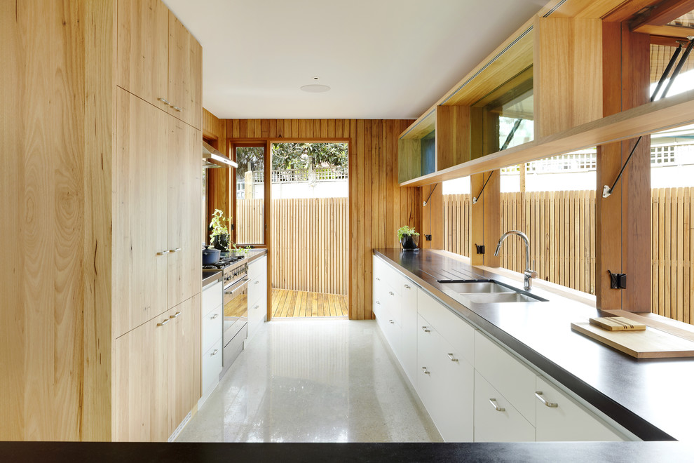 This is an example of a contemporary galley kitchen in Melbourne with flat-panel cabinets and white cabinets.
