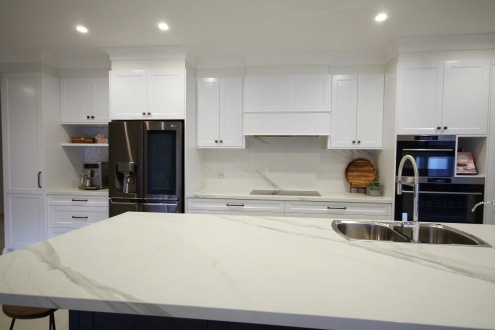 Idéer för att renovera ett stort vintage vit vitt kök, med en nedsänkt diskho, skåp i shakerstil, vita skåp, bänkskiva i kvarts, vitt stänkskydd, stänkskydd i marmor, rostfria vitvaror, klinkergolv i keramik, en köksö och grått golv