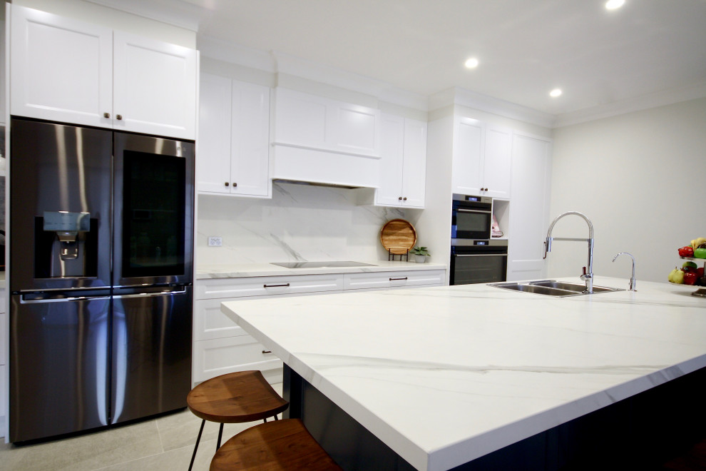 シドニーにあるラグジュアリーな広いトランジショナルスタイルのおしゃれなキッチン (ドロップインシンク、シェーカースタイル扉のキャビネット、白いキャビネット、クオーツストーンカウンター、白いキッチンパネル、大理石のキッチンパネル、シルバーの調理設備、セラミックタイルの床、グレーの床、白いキッチンカウンター) の写真