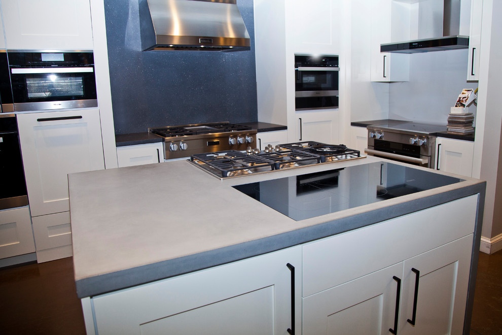 Immagine di una cucina industriale con ante in stile shaker, ante bianche, paraspruzzi grigio, elettrodomestici in acciaio inossidabile, pavimento in cemento e pavimento marrone