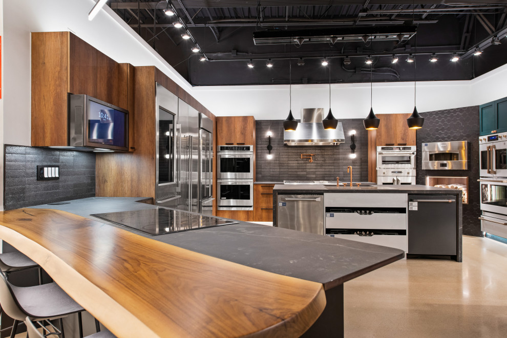 Example of a mid-sized trendy l-shaped beige floor open concept kitchen design in Austin with an undermount sink, flat-panel cabinets, medium tone wood cabinets, black backsplash, stainless steel appliances, an island and beige countertops