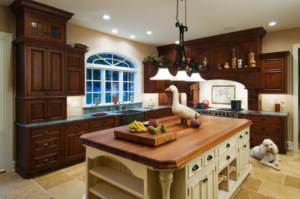 Exempel på ett stort amerikanskt kök, med en rustik diskho, luckor med upphöjd panel, skåp i mörkt trä, bänkskiva i täljsten, beige stänkskydd, stänkskydd i keramik, rostfria vitvaror, kalkstensgolv, en köksö och beiget golv