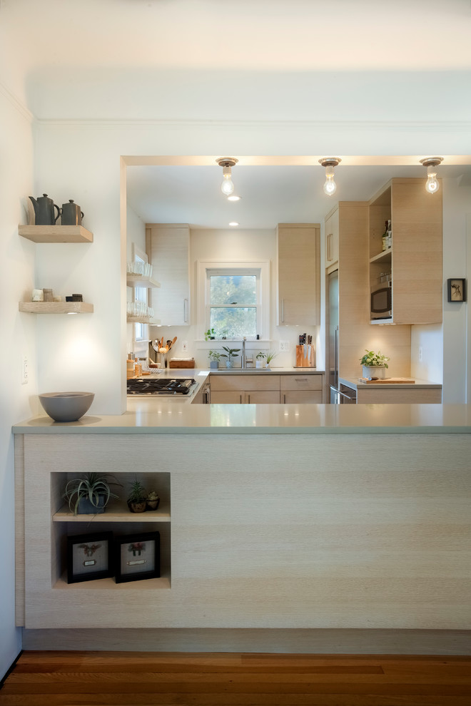 Foto di una cucina minimalista con lavello sottopiano, ante lisce, ante in legno chiaro, elettrodomestici in acciaio inossidabile e parquet chiaro
