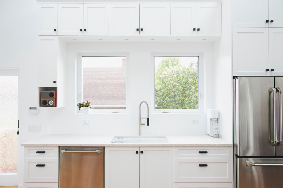 Minimalist u-shaped eat-in kitchen photo in Vancouver with an undermount sink, shaker cabinets, white cabinets, quartzite countertops, white backsplash, stainless steel appliances and a peninsula