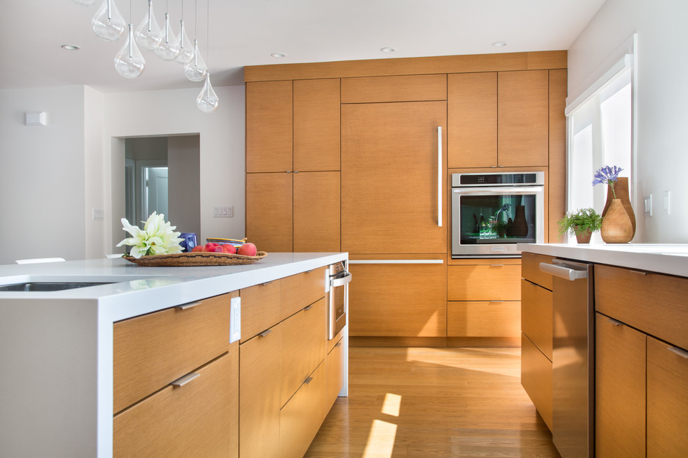 Large trendy light wood floor open concept kitchen photo in San Francisco with an undermount sink, flat-panel cabinets, medium tone wood cabinets, quartz countertops, white backsplash, glass sheet backsplash, stainless steel appliances and an island
