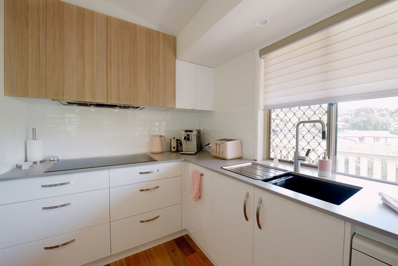 Offene, Große Moderne Küche in L-Form mit Glasfronten, schwarzen Schränken, Quarzwerkstein-Arbeitsplatte, hellem Holzboden und Kücheninsel in Brisbane