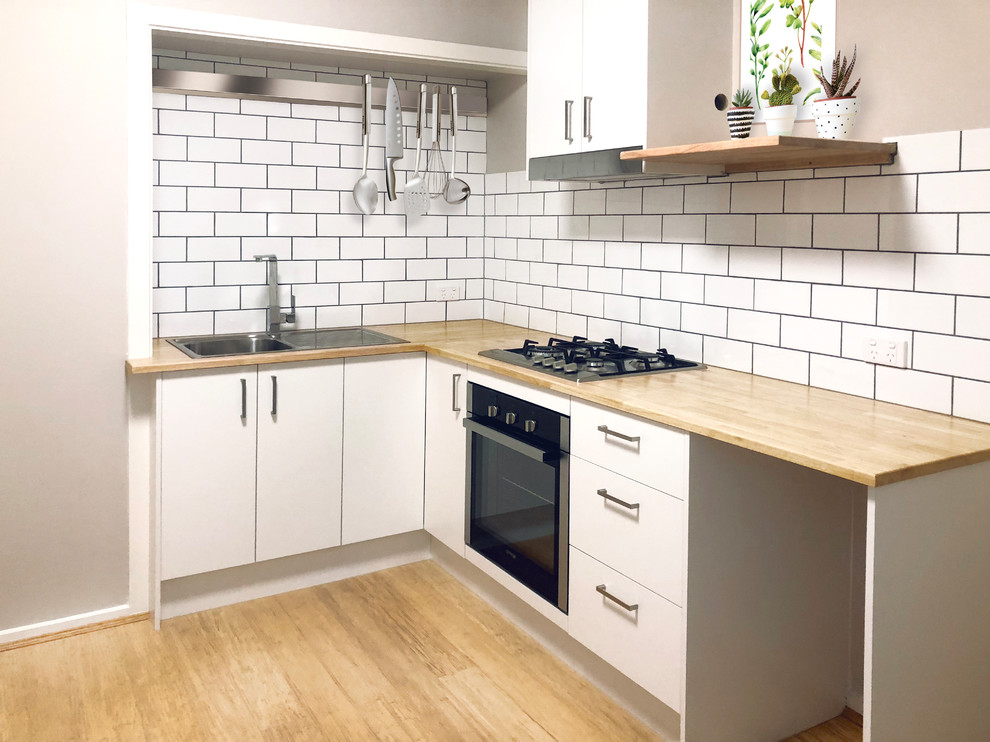Offene, Kleine Moderne Küche ohne Insel in L-Form mit Küchenrückwand in Weiß, Rückwand aus Metrofliesen, Küchengeräten aus Edelstahl und Bambusparkett in Melbourne