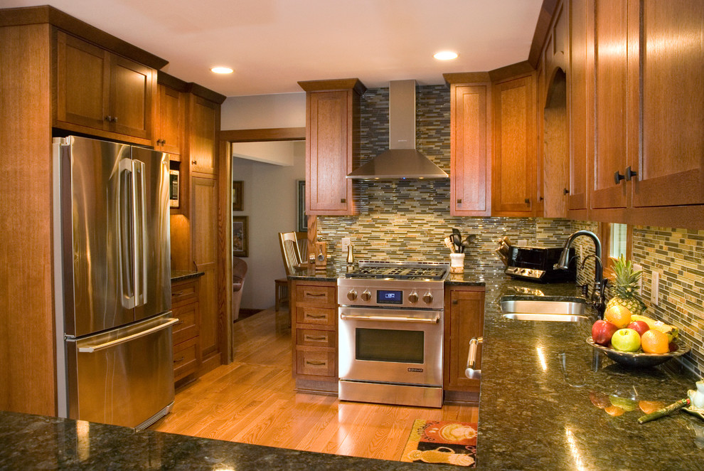 Example of a mid-sized arts and crafts l-shaped medium tone wood floor open concept kitchen design in Minneapolis with a double-bowl sink, shaker cabinets, medium tone wood cabinets, granite countertops, gray backsplash, mosaic tile backsplash, stainless steel appliances and a peninsula