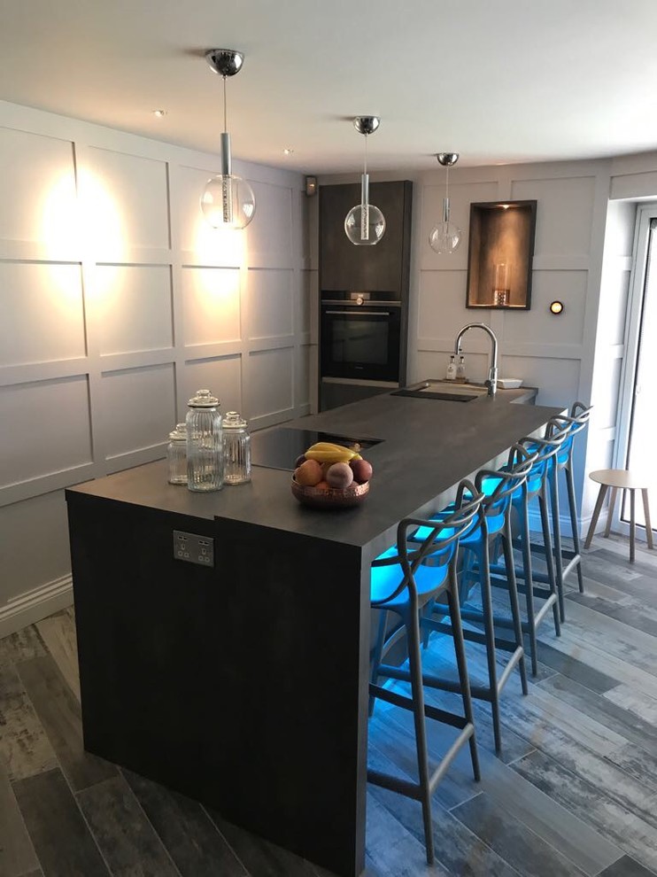 Foto på ett mellanstort funkis kök och matrum, med grå skåp, svarta vitvaror, laminatgolv, flera köksöar och grått golv