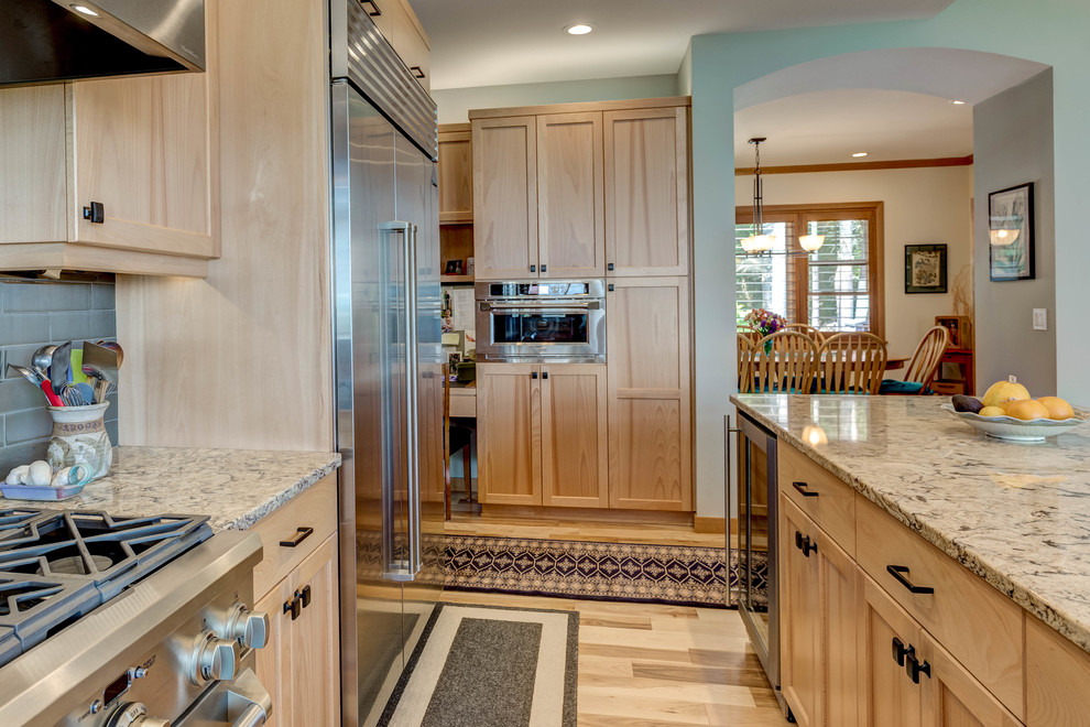 Design ideas for a medium sized traditional l-shaped open plan kitchen in Seattle with shaker cabinets, light wood cabinets, engineered stone countertops, green splashback, porcelain splashback, stainless steel appliances, light hardwood flooring and an island.