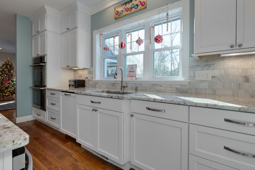 This is an example of a large classic u-shaped open plan kitchen in Boston with a submerged sink, shaker cabinets, white cabinets, granite worktops, stainless steel appliances, medium hardwood flooring and an island.
