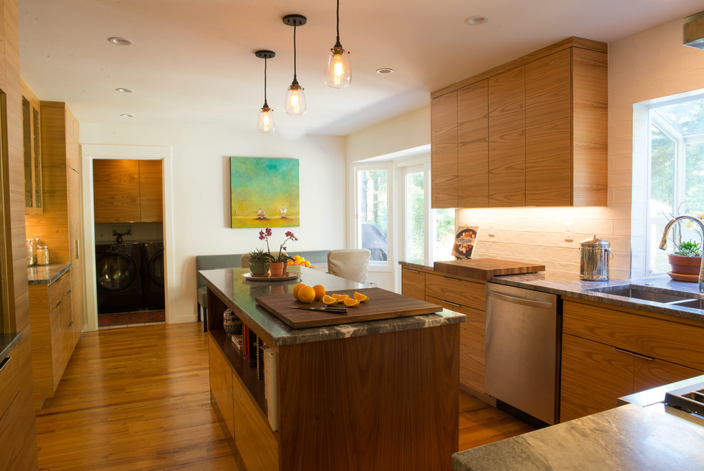 Cette image montre une cuisine américaine minimaliste en bois clair avec un électroménager en acier inoxydable et îlot.