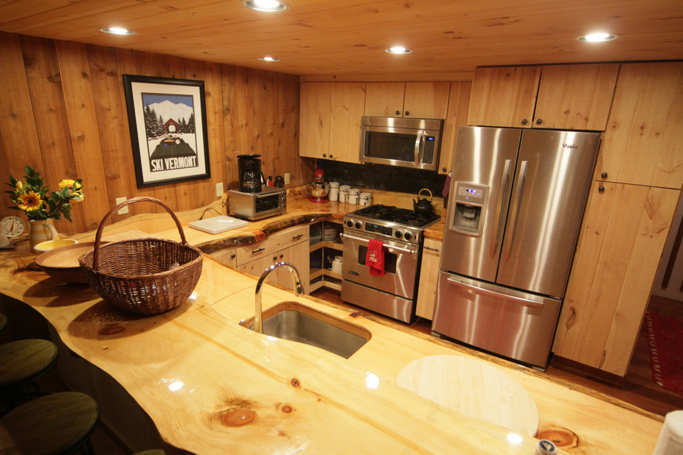 Bild på ett mellanstort amerikanskt kök, med en undermonterad diskho, släta luckor, skåp i ljust trä, träbänkskiva, stänkskydd med metallisk yta, stänkskydd i metallkakel, rostfria vitvaror, mellanmörkt trägolv och en halv köksö