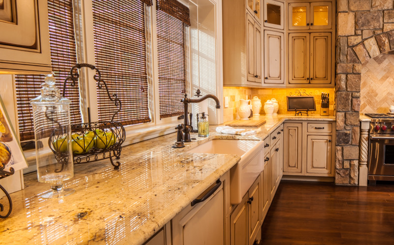 Immagine di una cucina country di medie dimensioni con ante bianche, top in granito, paraspruzzi beige e pavimento in legno massello medio