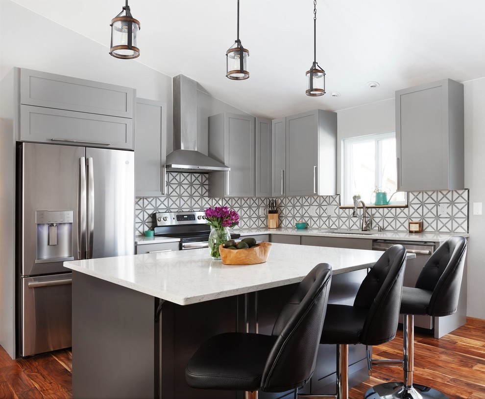 Moderne Küche in L-Form mit Unterbauwaschbecken, Schrankfronten im Shaker-Stil, grauen Schränken, Küchenrückwand in Weiß, Küchengeräten aus Edelstahl, braunem Holzboden, Kücheninsel, braunem Boden und weißer Arbeitsplatte in Denver