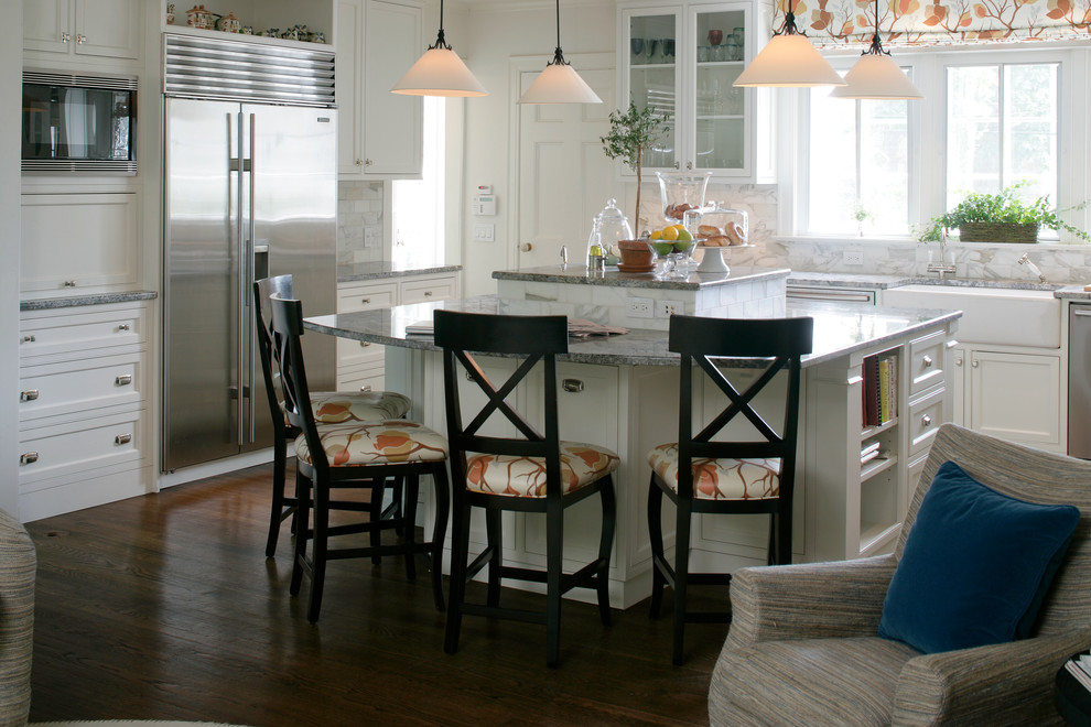 Foto på ett stort lantligt kök, med en rustik diskho, luckor med infälld panel, vita skåp, granitbänkskiva, flerfärgad stänkskydd, stänkskydd i marmor, rostfria vitvaror, mörkt trägolv, en köksö och brunt golv