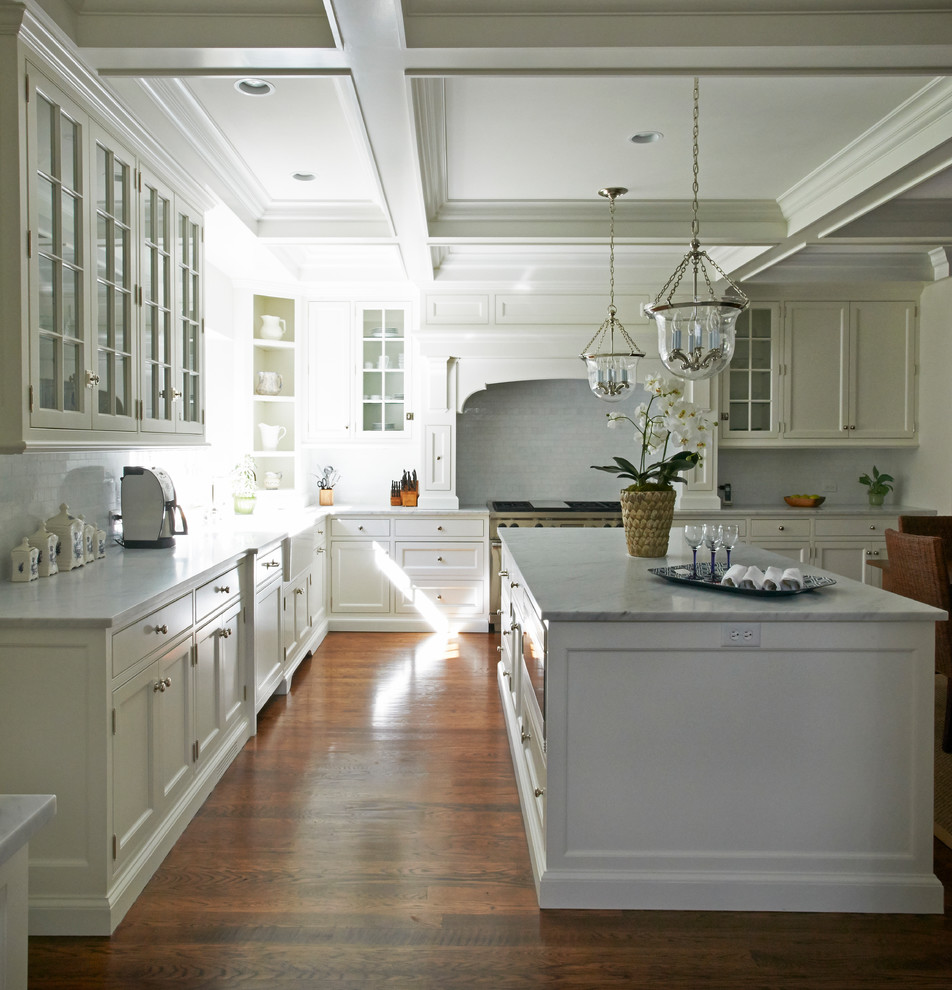 Foto di una cucina classica con lavello sottopiano, ante lisce, ante bianche, top in marmo, paraspruzzi bianco, paraspruzzi con piastrelle di vetro, elettrodomestici da incasso e pavimento in legno massello medio