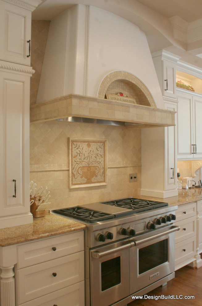 Foto på ett stort vintage kök, med en undermonterad diskho, luckor med upphöjd panel, vita skåp, granitbänkskiva, beige stänkskydd, stänkskydd i stenkakel, rostfria vitvaror, mellanmörkt trägolv, en köksö och brunt golv