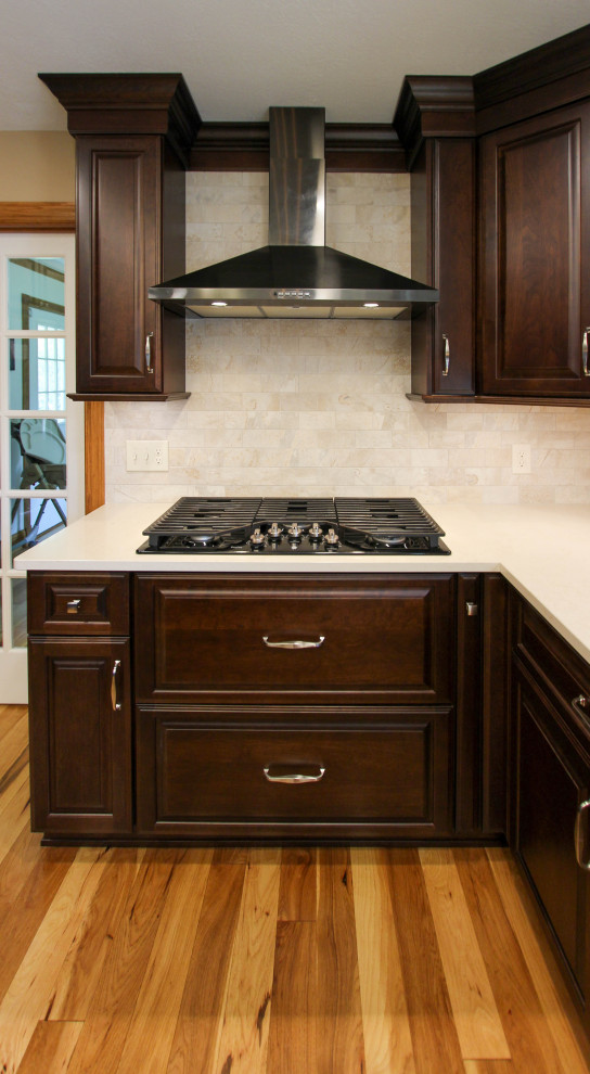 Inspiration for a mid-sized timeless u-shaped light wood floor eat-in kitchen remodel in Cleveland with an undermount sink, raised-panel cabinets, dark wood cabinets, quartz countertops, beige backsplash, ceramic backsplash, black appliances, an island and beige countertops