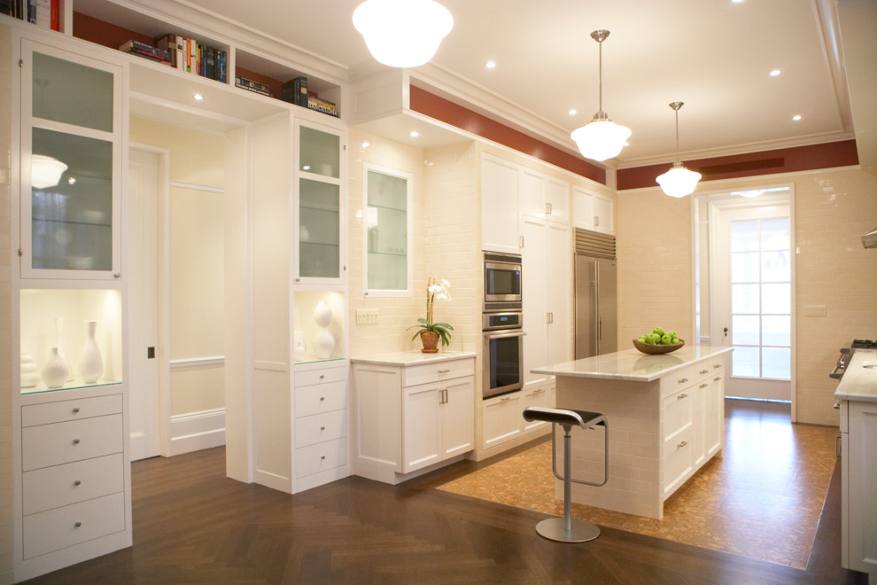 Exempel på ett stort modernt kök, med en undermonterad diskho, släta luckor, vita skåp, bänkskiva i kalksten, beige stänkskydd, stänkskydd i tunnelbanekakel, rostfria vitvaror, korkgolv och en köksö